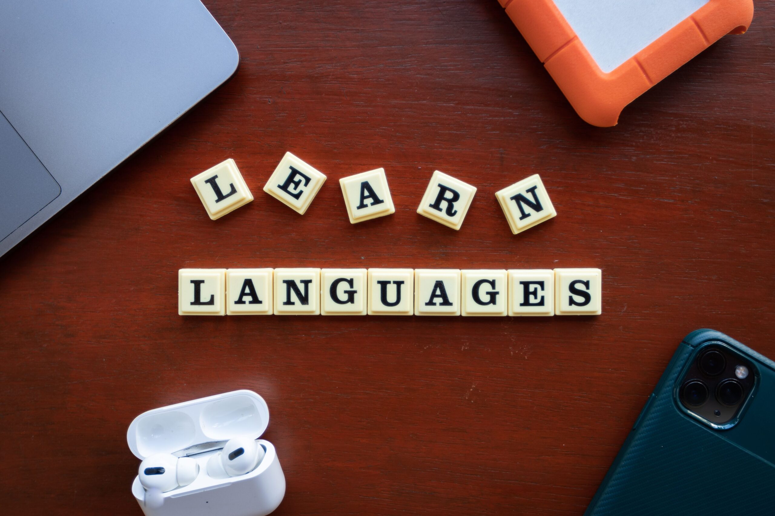 Language learning letters arranged beside a laptop and mobile devices