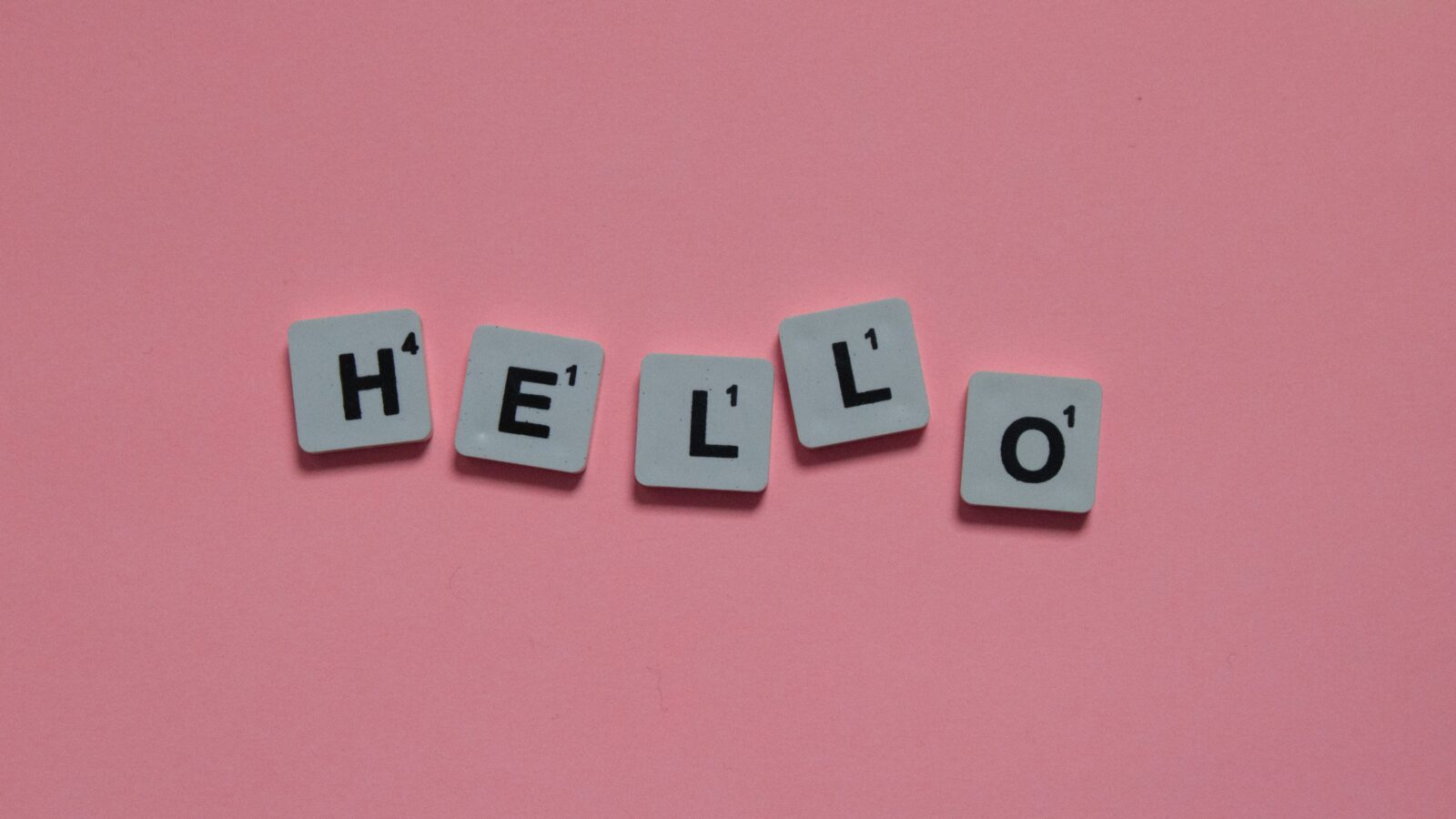 Pale blue letter tiles spelling HELLO on a pink background, representing multilingual translation