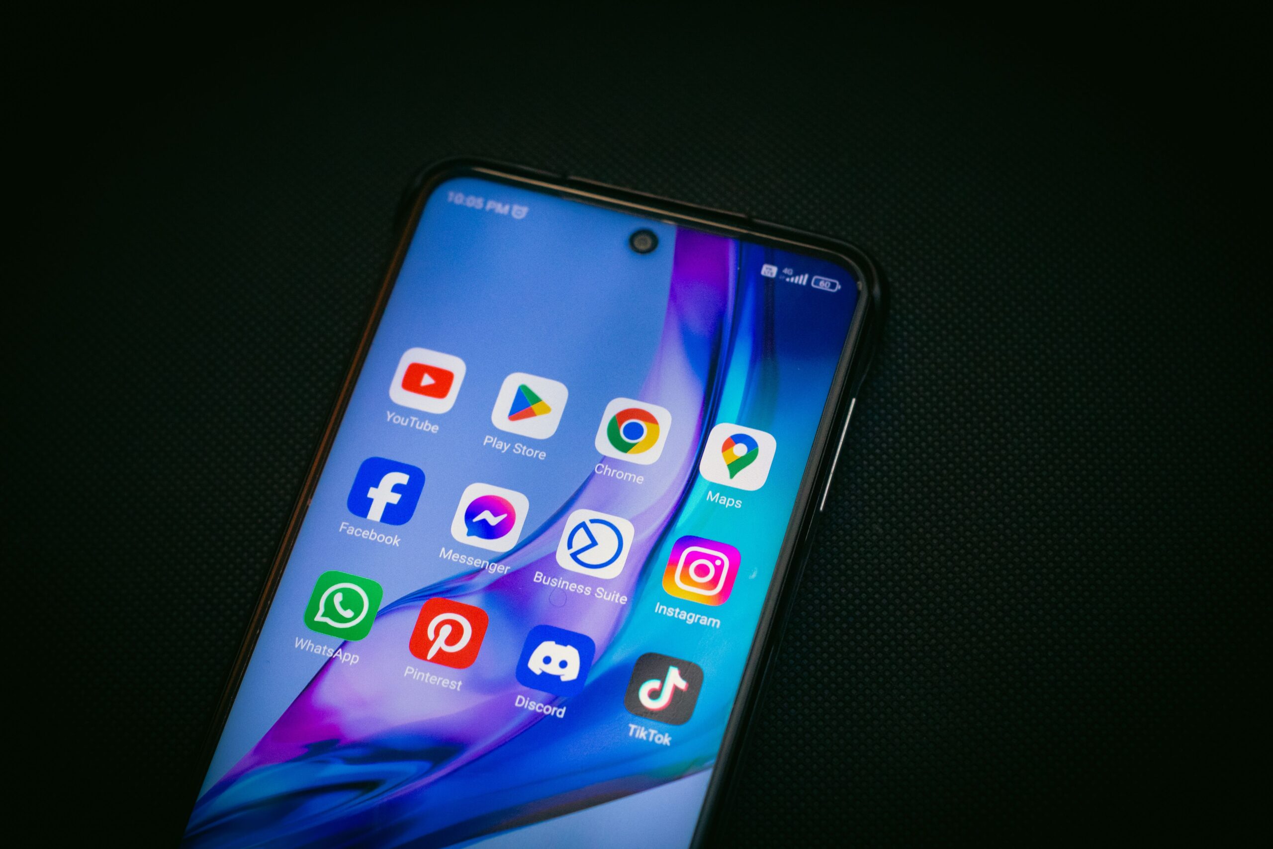 indraprojectsofficial, Pexels License, via https://www.pexels.com/photo/icons-on-smartphone-touchscreen-18663994/ A smartphone home screen that includes the Discord app icon among other apps, the surface a translator bot works on