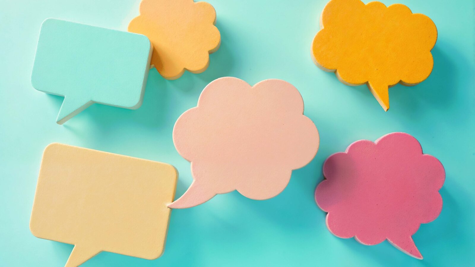Pastel speech bubbles in several colours on a light turquoise background, illustrating a multilingual chat