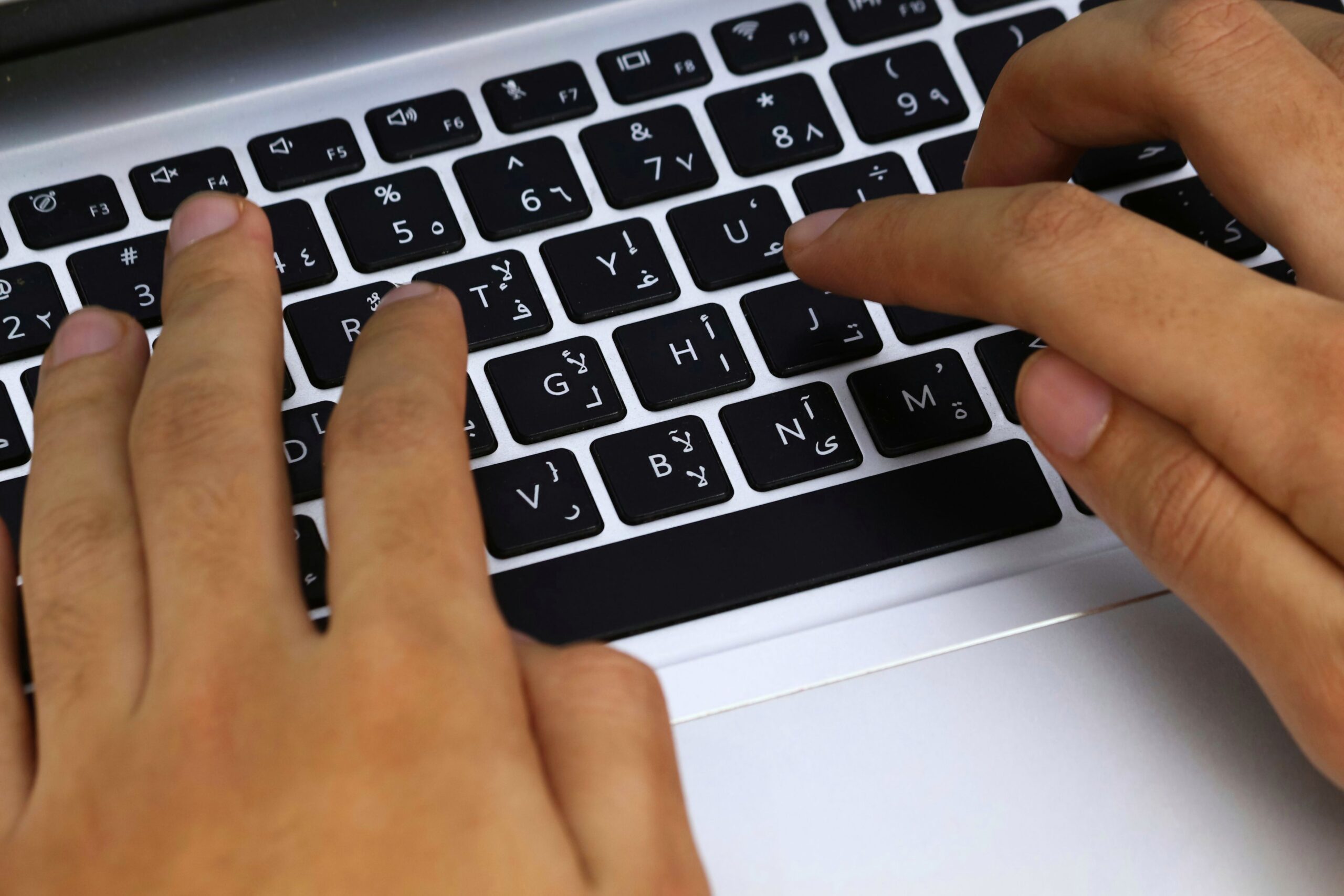 Bilingual Arabic and English laptop keyboard, the right-to-left script sitting beside a Latin one among the supported languages