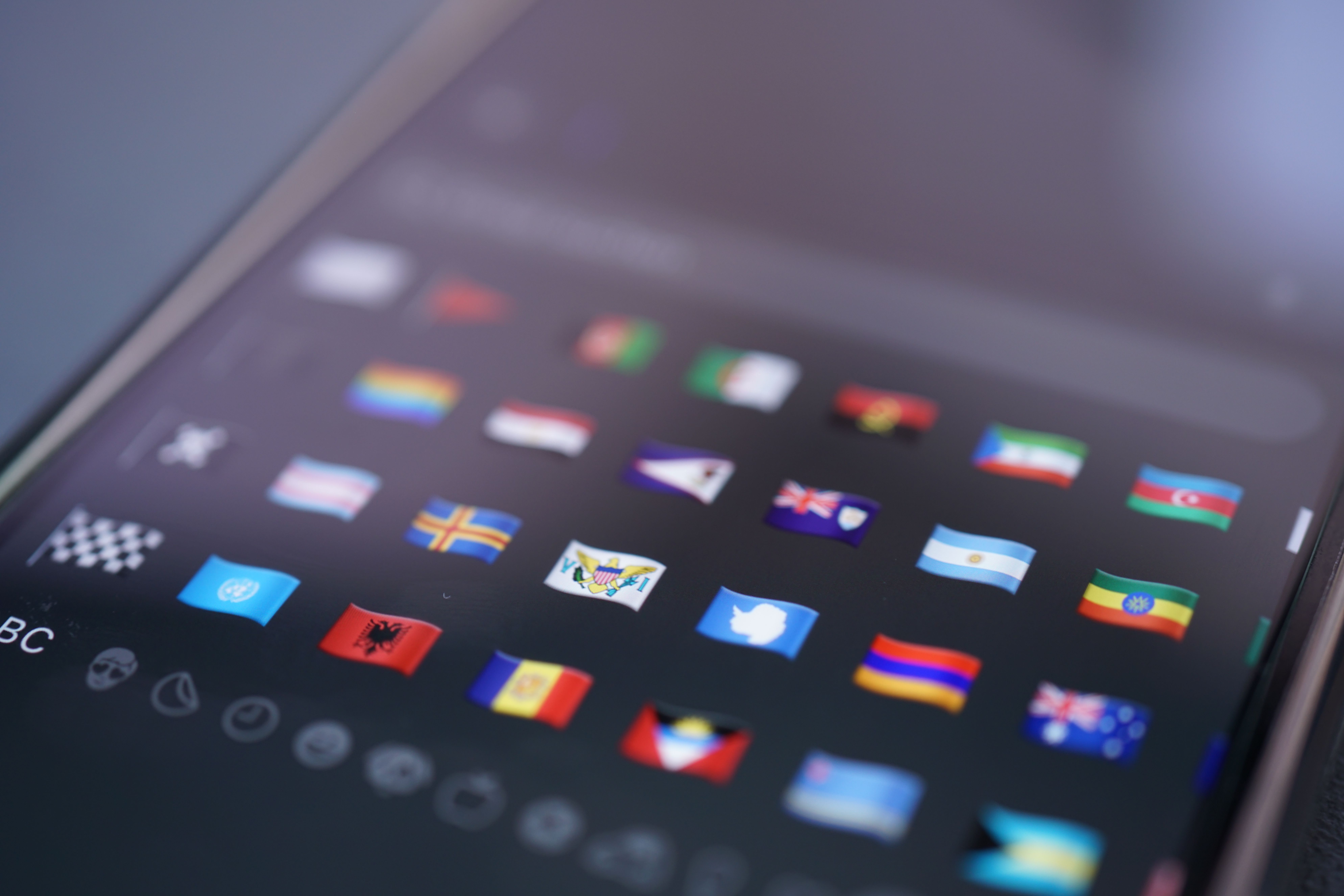 A smartphone showing a grid of world flag emojis, the language picker for a flag-based translation command