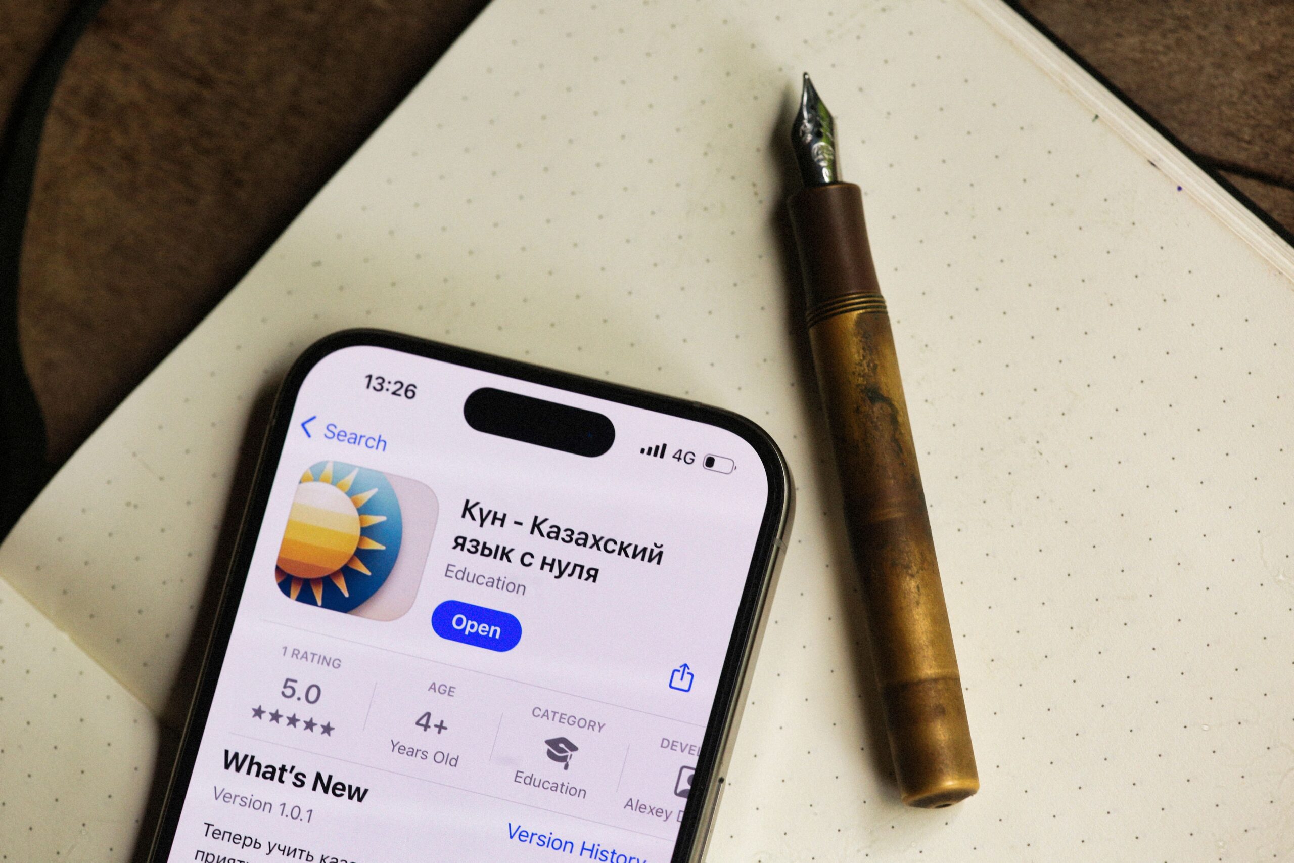 alexeydemidov, Pexels License, via Pexels Smartphone next to notebook showing a language learning app, illustrating the concept of connecting language tools to technology