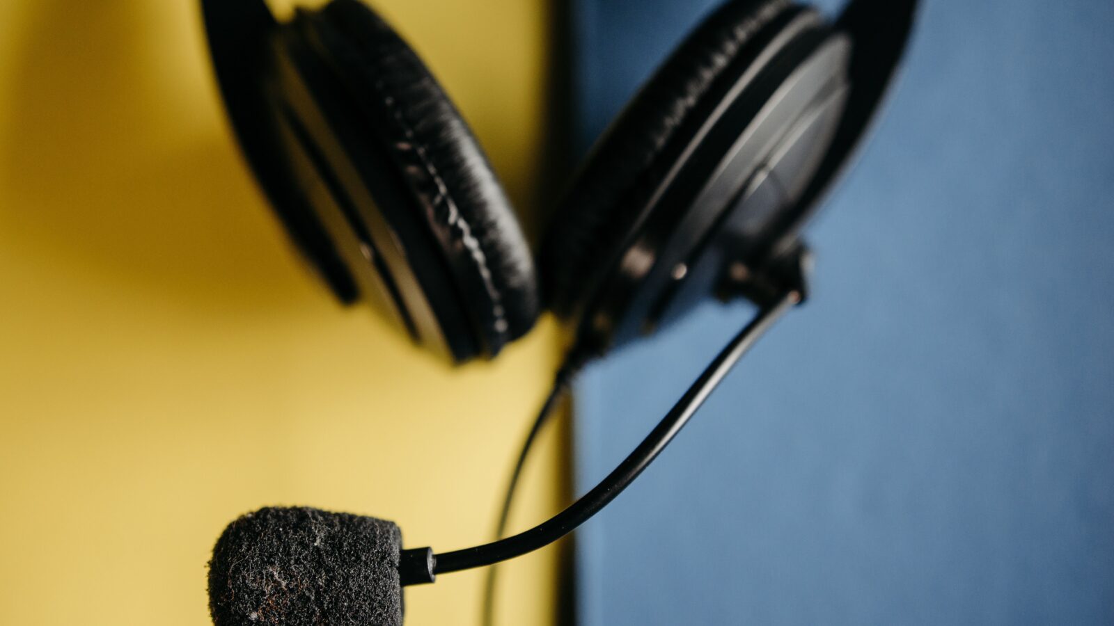 A black over-ear headset with a boom microphone against a yellow and blue backdrop