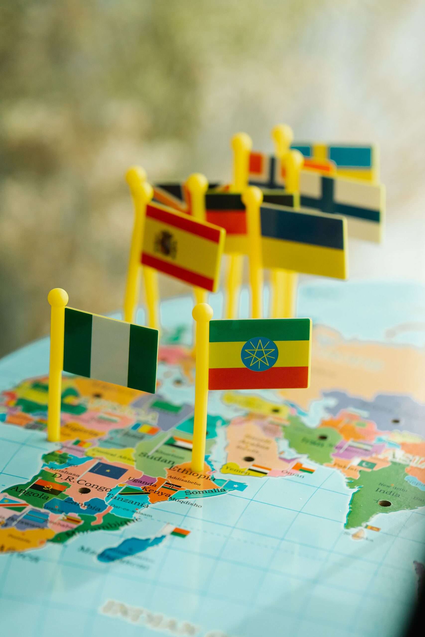small toy country flags pinned on a world globe
