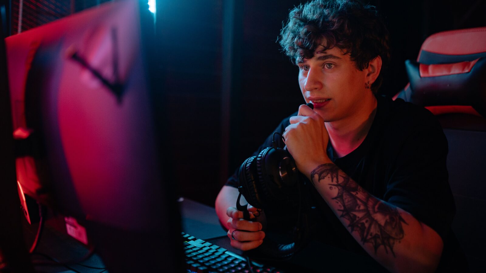 A person in a black shirt speaking into a headset microphone while looking at a computer monitor
