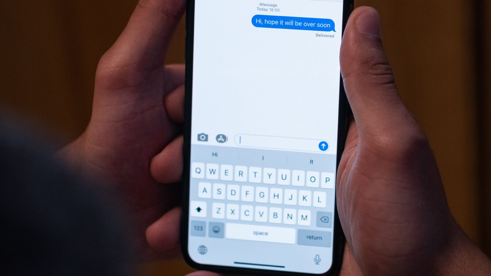 A person holding a smartphone with a chat conversation open on the screen